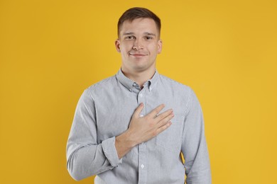 Photo of Man making promise on orange background. Oath gesture