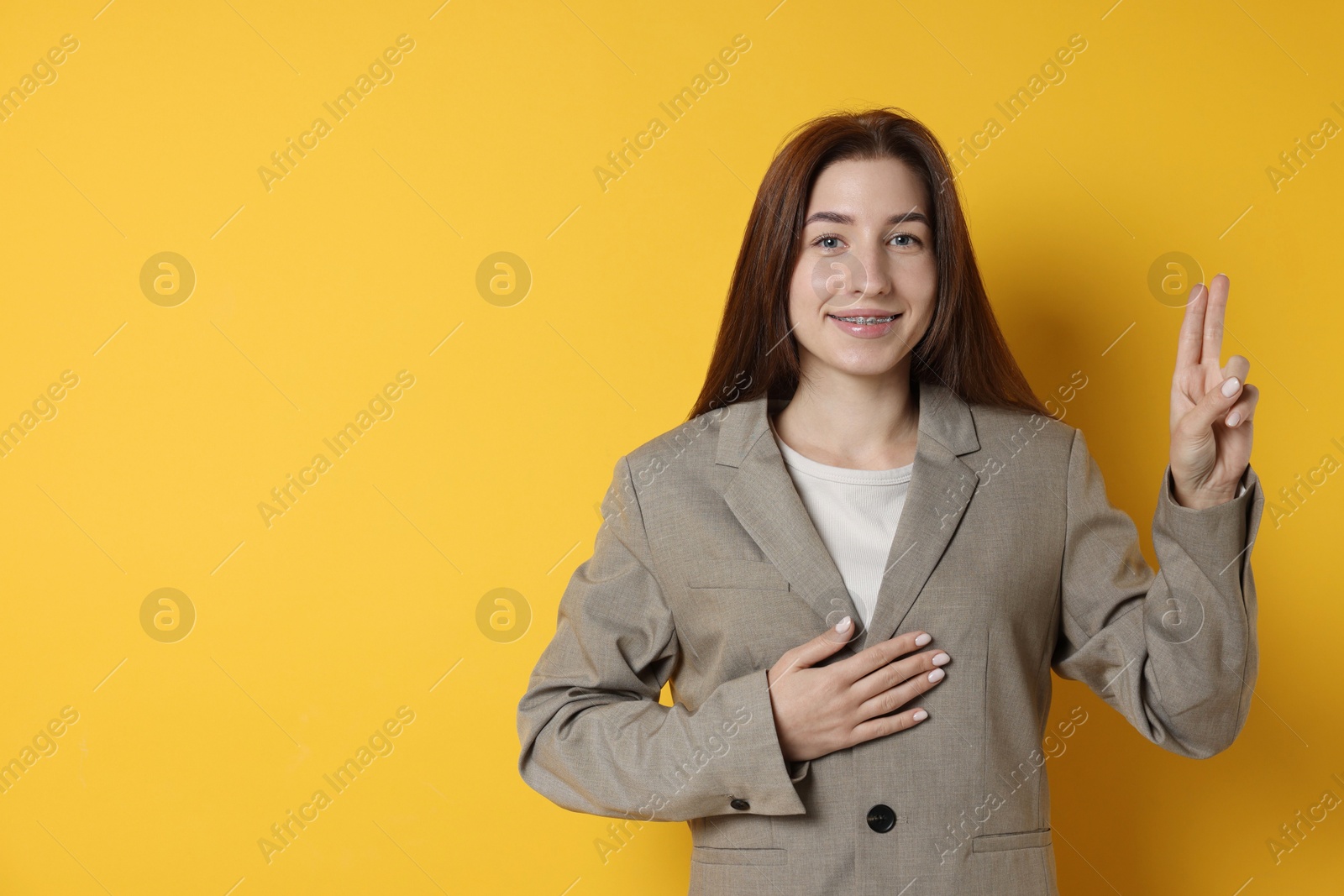 Photo of Woman showing oath gesture on orange background, space for text. Making promise