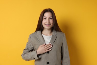 Woman making promise on orange background. Oath gesture