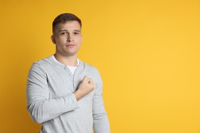 Photo of Man making promise on orange background, space for text. Oath gesture