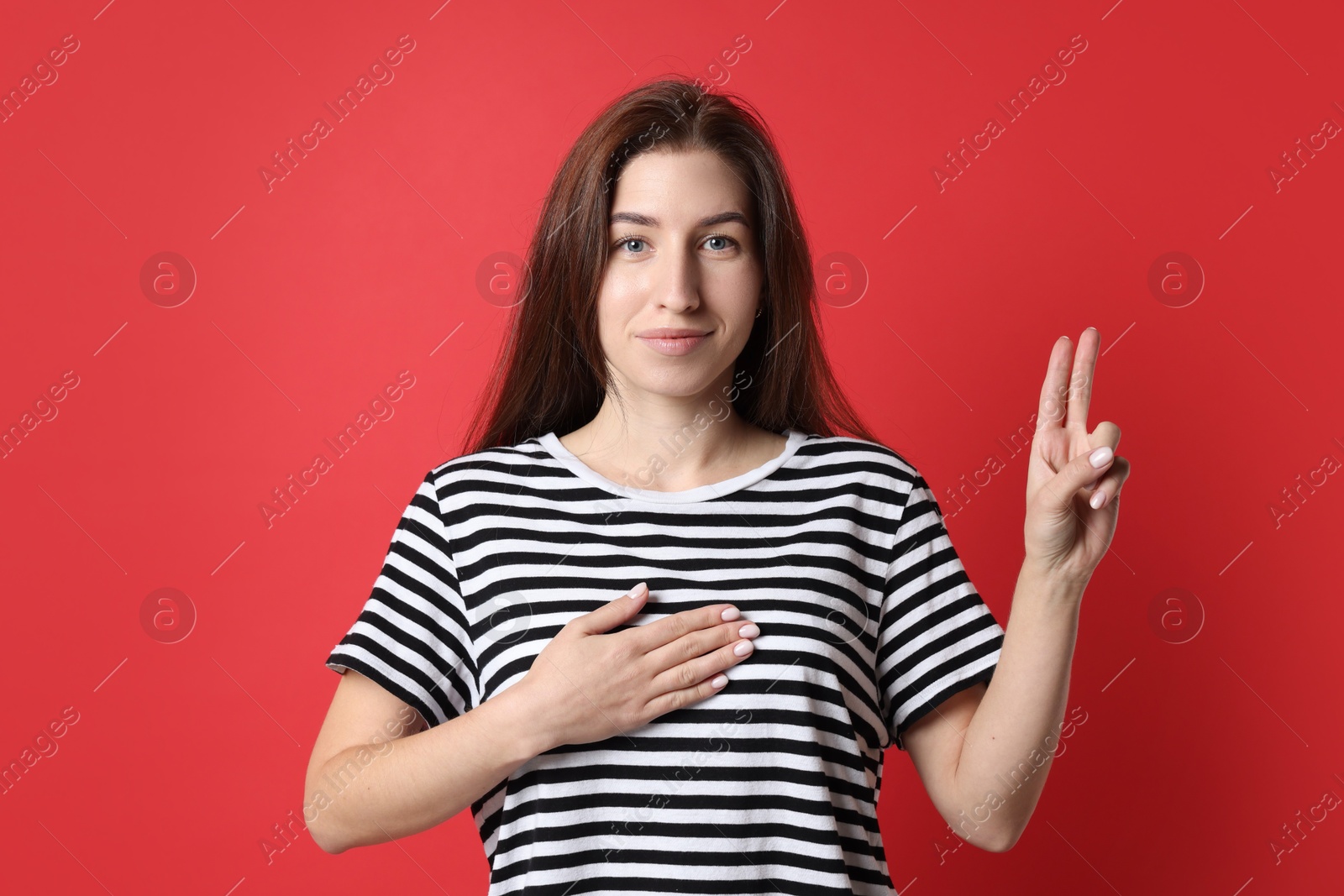 Photo of Woman showing oath gesture on red background. Making promise