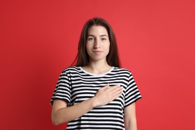 Photo of Woman making promise on red background. Oath gesture