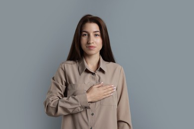 Photo of Woman making promise on grey background. Oath gesture