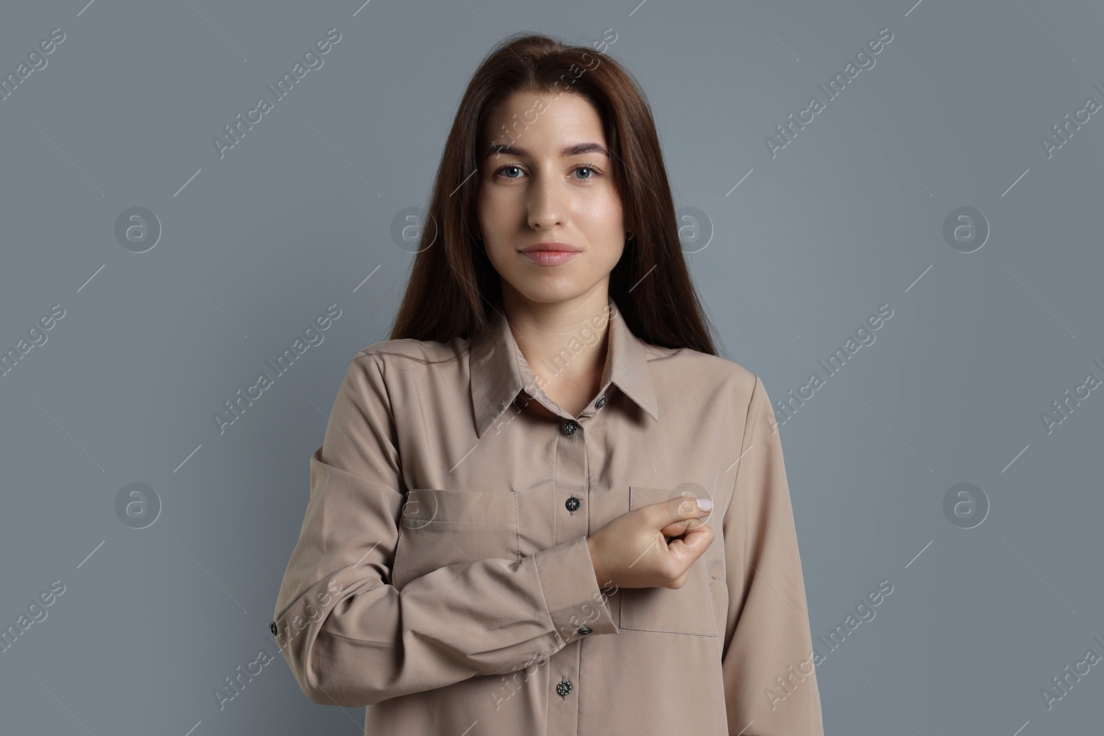 Photo of Woman making promise on grey background. Oath gesture