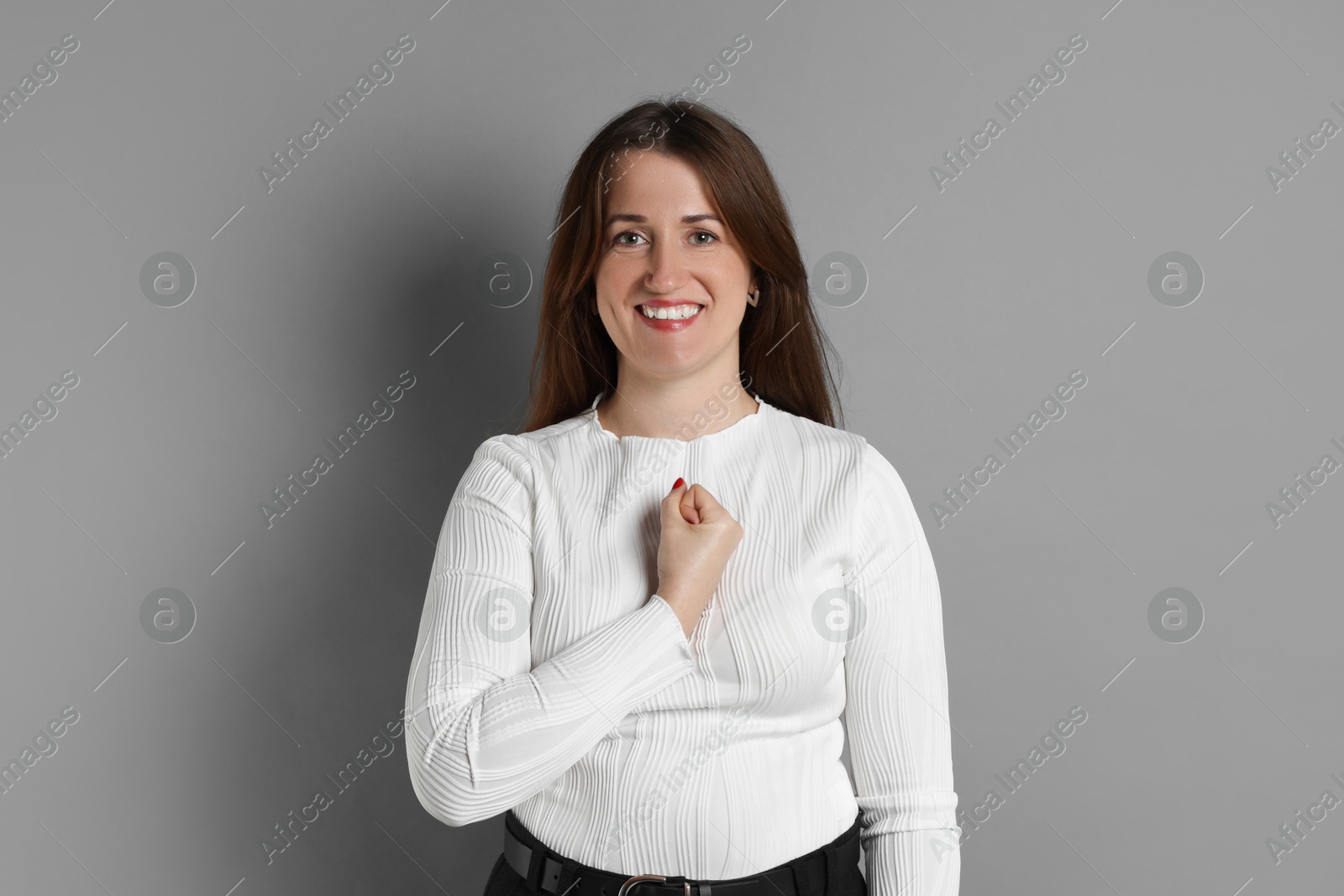 Photo of Woman making promise on grey background. Oath gesture