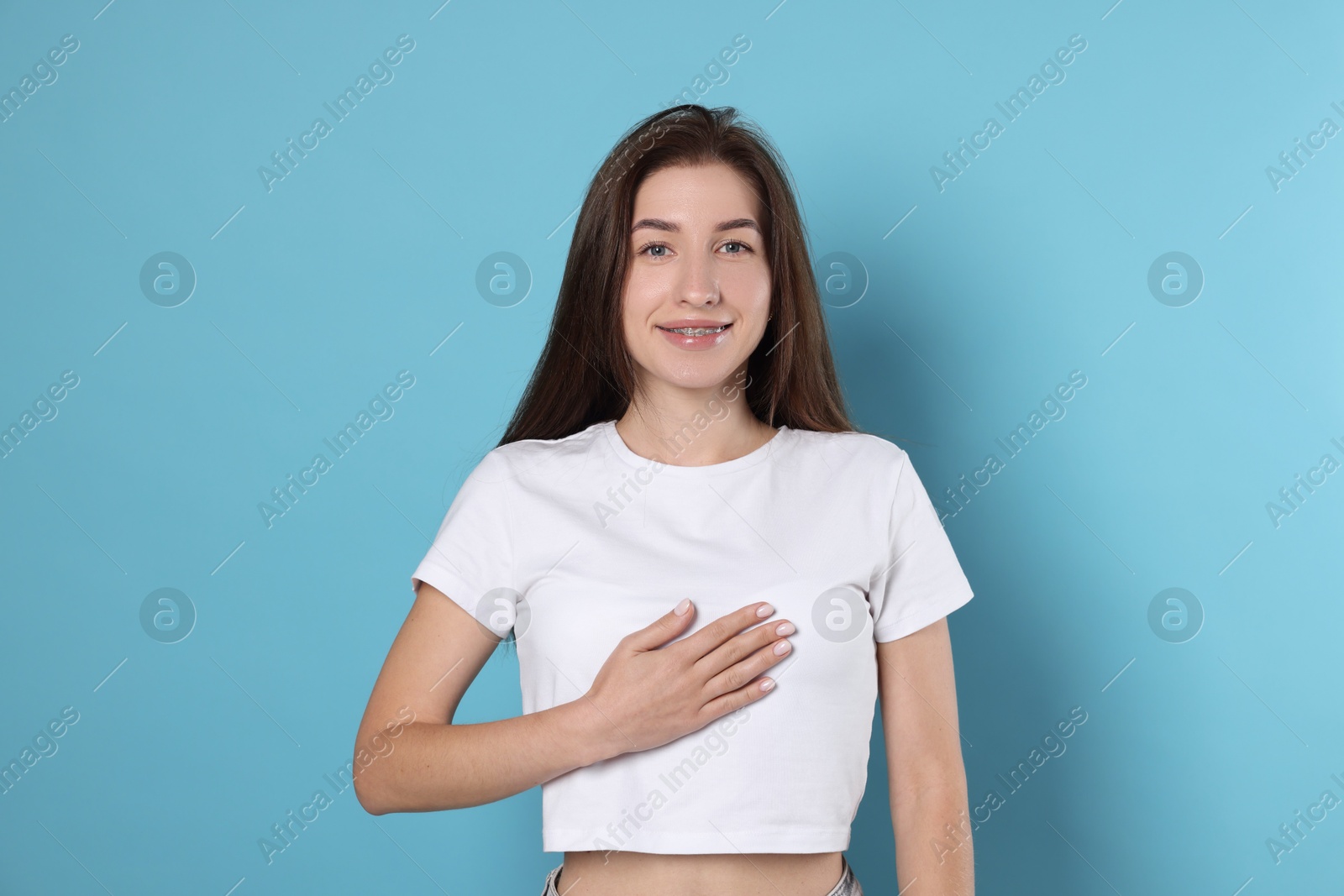 Photo of Woman making promise on light blue background. Oath gesture