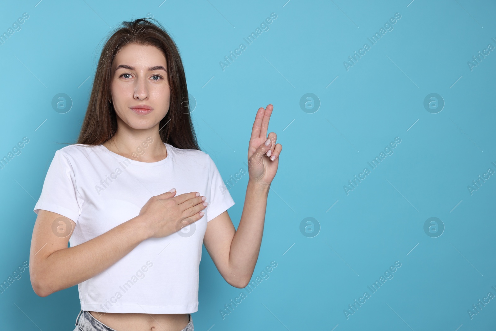 Photo of Woman showing oath gesture on light blue background, space for text. Making promise