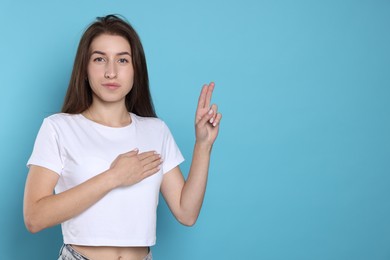 Photo of Woman showing oath gesture on light blue background, space for text. Making promise