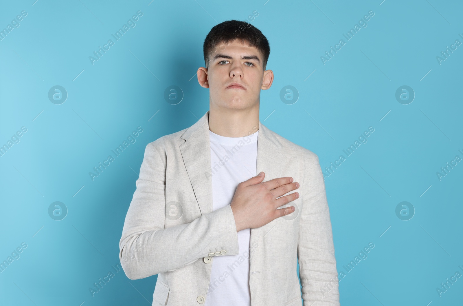 Photo of Man making promise on light blue background. Oath gesture