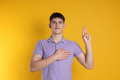 Photo of Man showing oath gesture on orange background