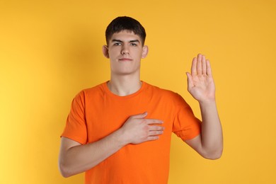 Man showing oath gesture on orange background