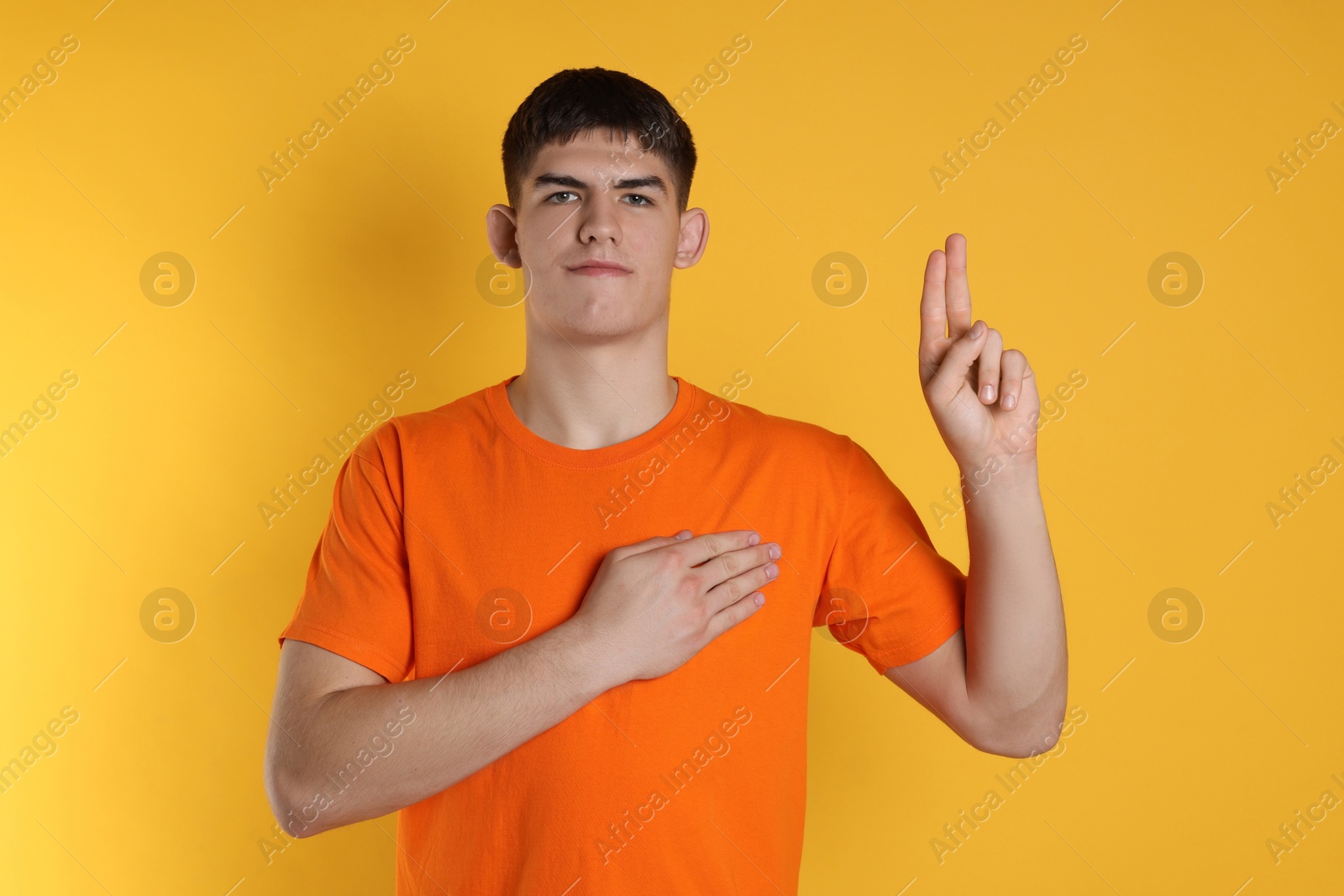 Photo of Man showing oath gesture on orange background