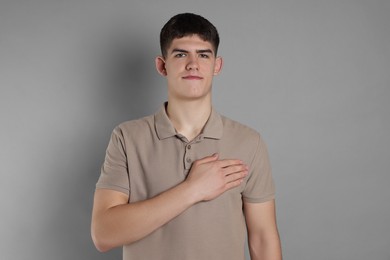 Man showing oath gesture on grey background