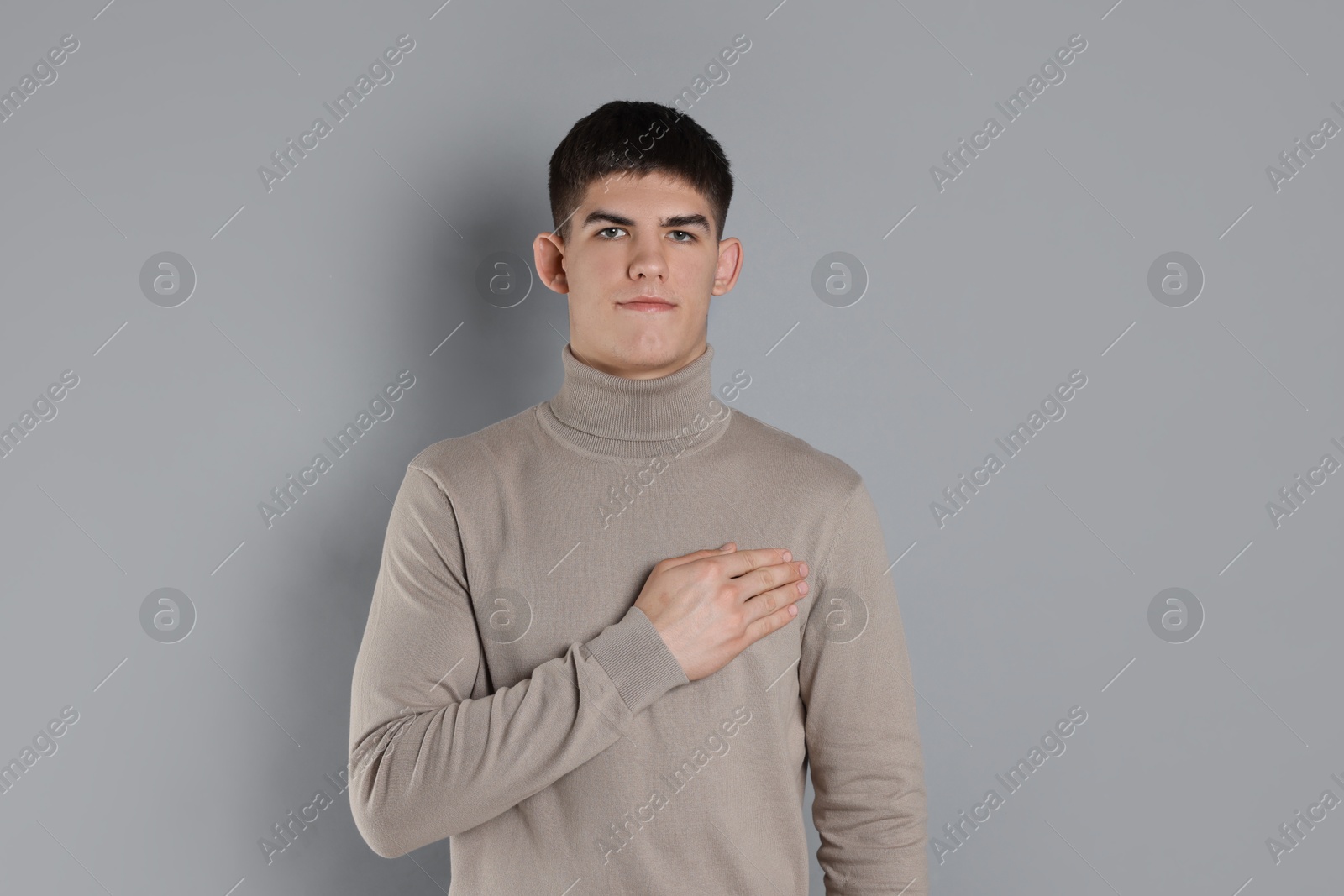 Photo of Man showing oath gesture on grey background