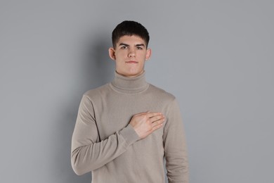 Man showing oath gesture on grey background