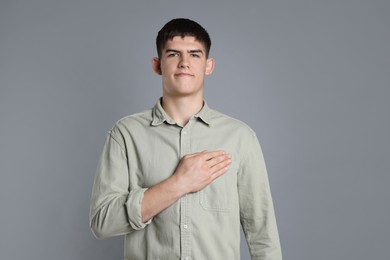 Man showing oath gesture on grey background