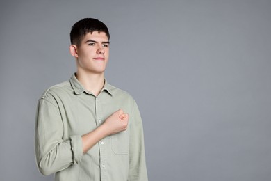 Man showing oath gesture on grey background. Space for text