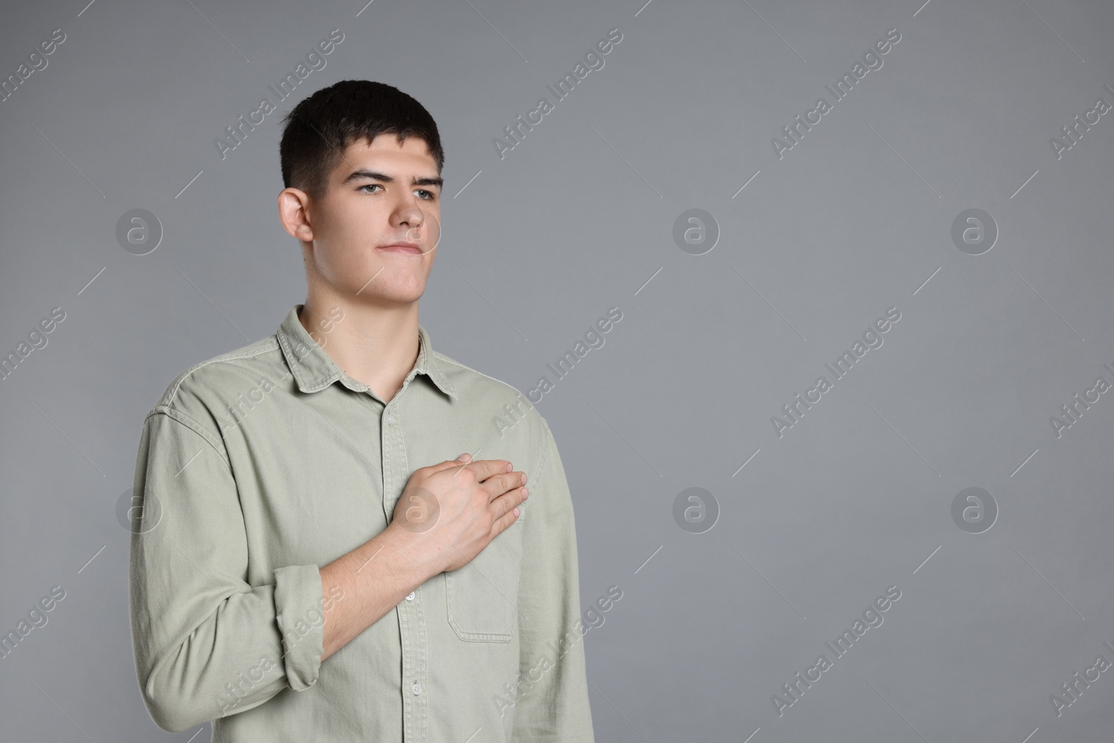 Photo of Man showing oath gesture on grey background. Space for text