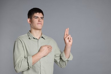 Photo of Man showing oath gesture on grey background. Space for text