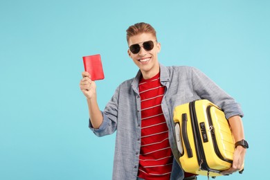 Photo of Happy traveller with suitcase and passport on light blue background