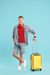 Photo of Happy traveller with suitcase on light blue background