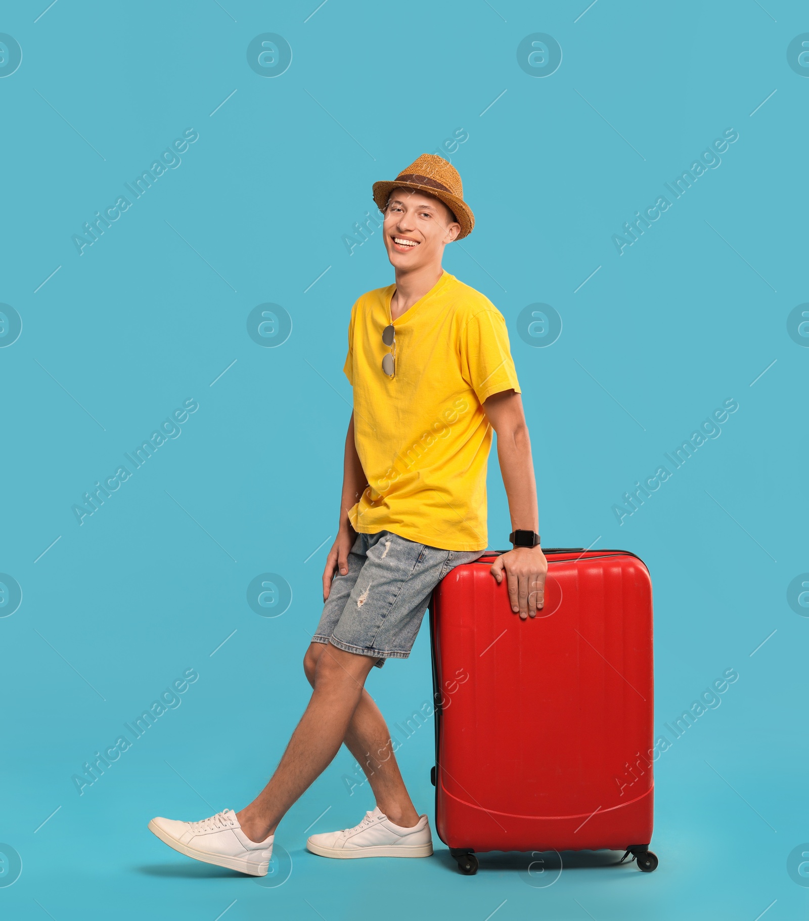 Photo of Happy traveller with suitcase on light blue background. Space for text