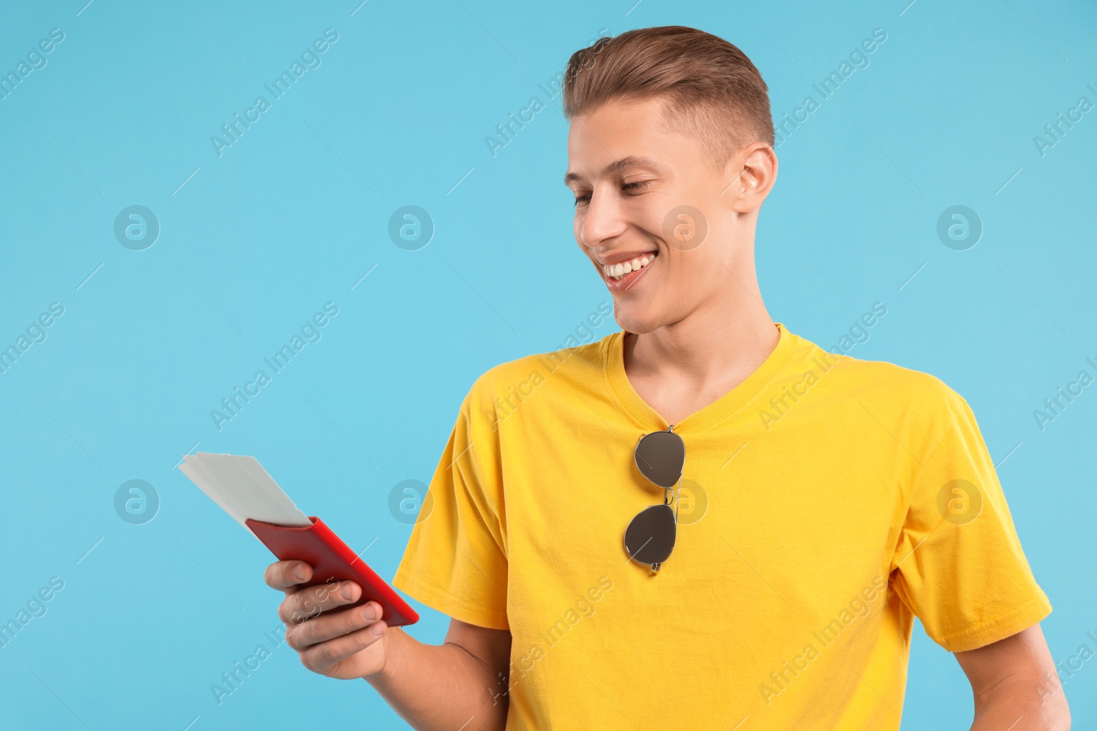 Photo of Happy traveller with passport and tickets on light blue background