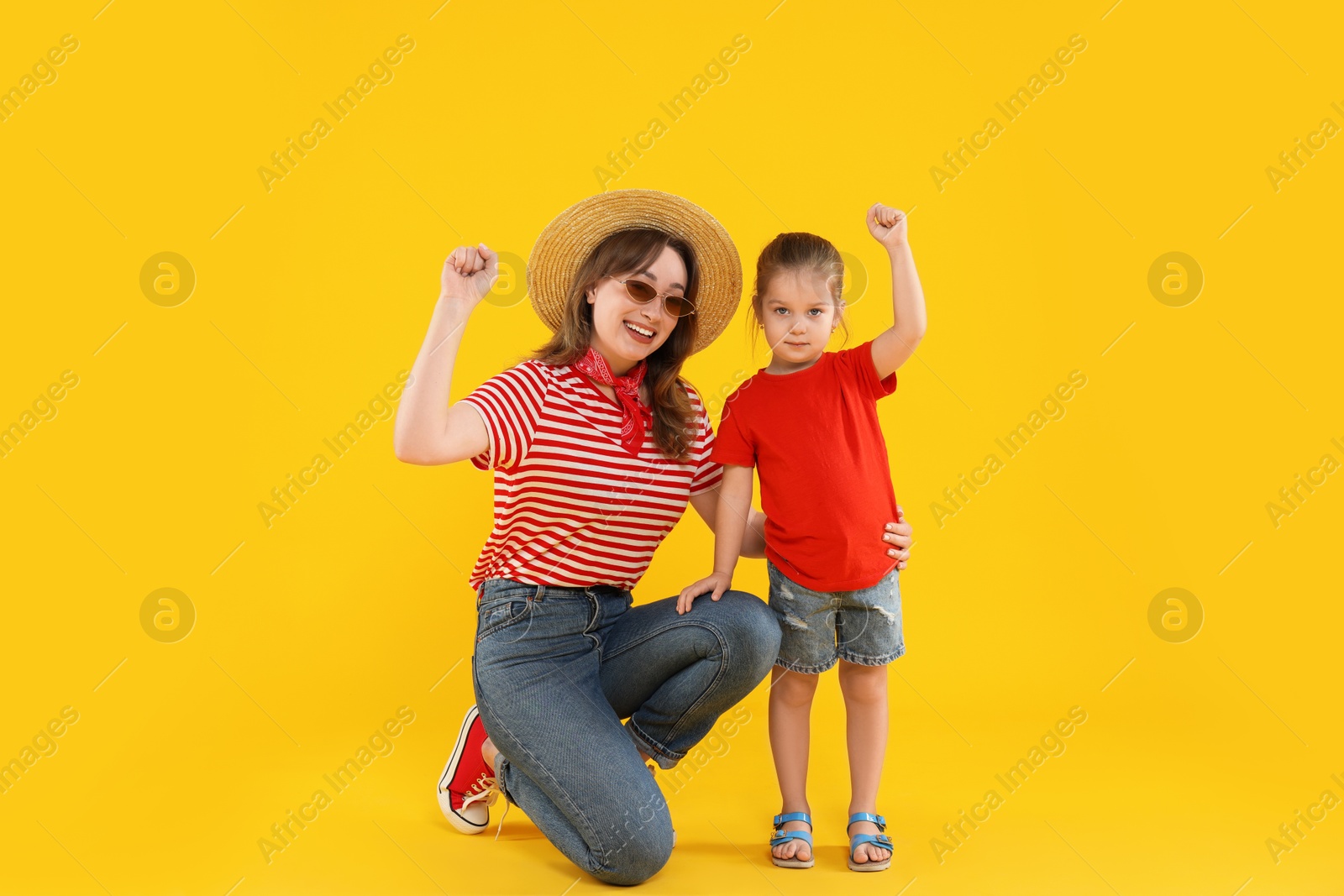 Photo of Happy young woman and cute little girl on yellow background