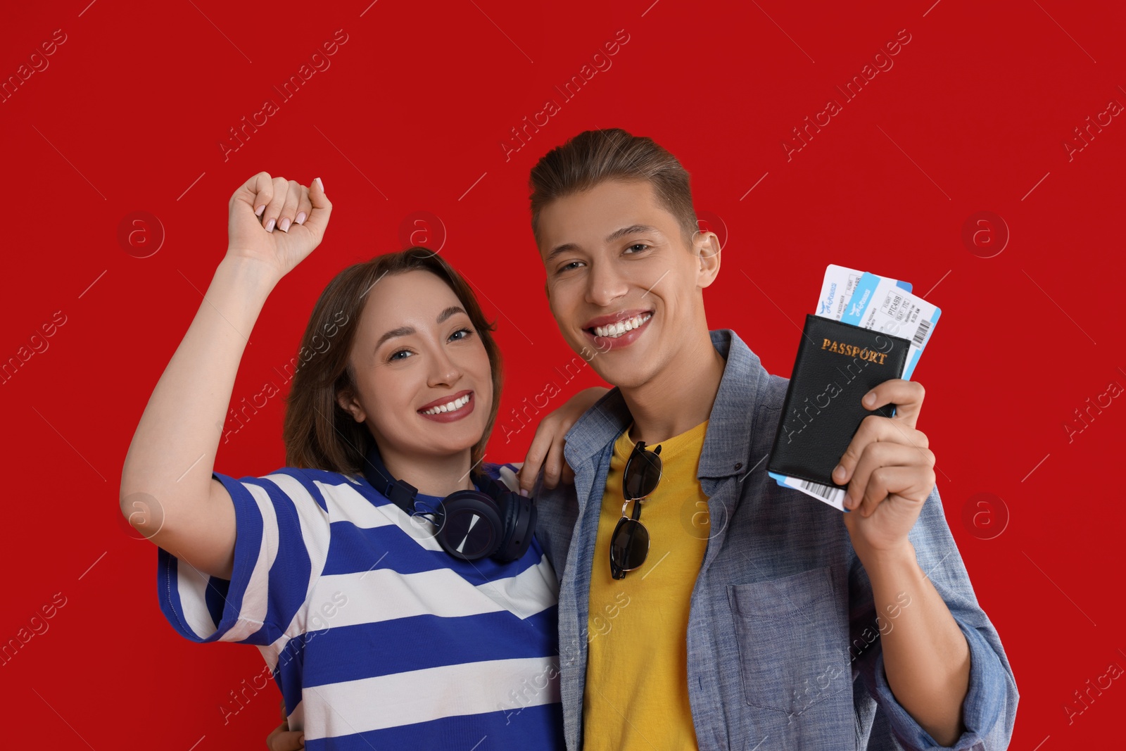 Photo of Happy travellers with passport and tickets on red background