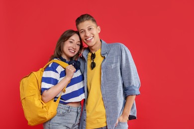 Photo of Traveller with backpack. Happy young woman and man on red background