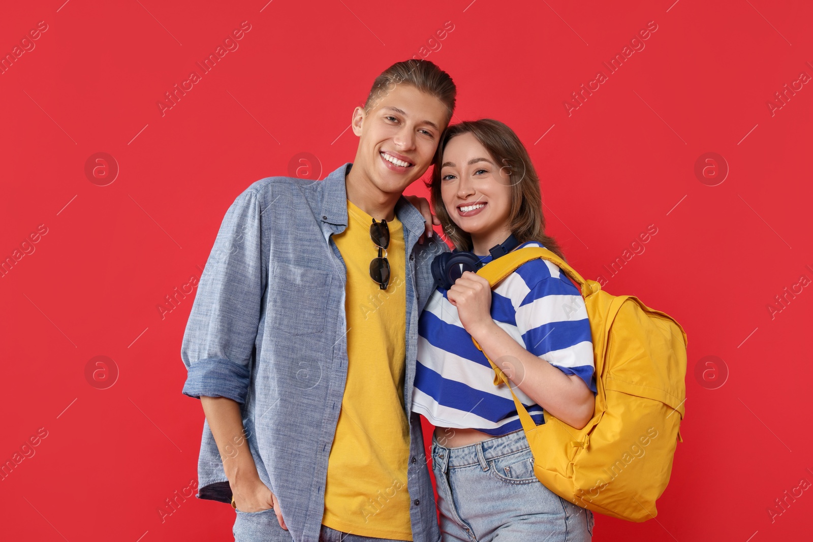 Photo of Traveller with backpack. Happy young woman and man on red background