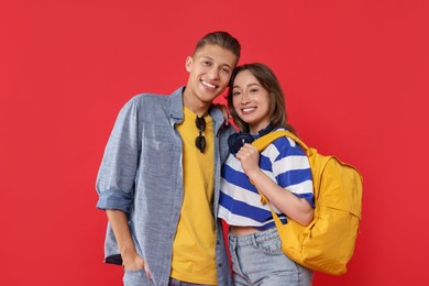 Photo of Traveller with backpack. Happy young woman and man on red background