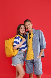 Photo of Traveller with backpack. Happy young woman and man on red background