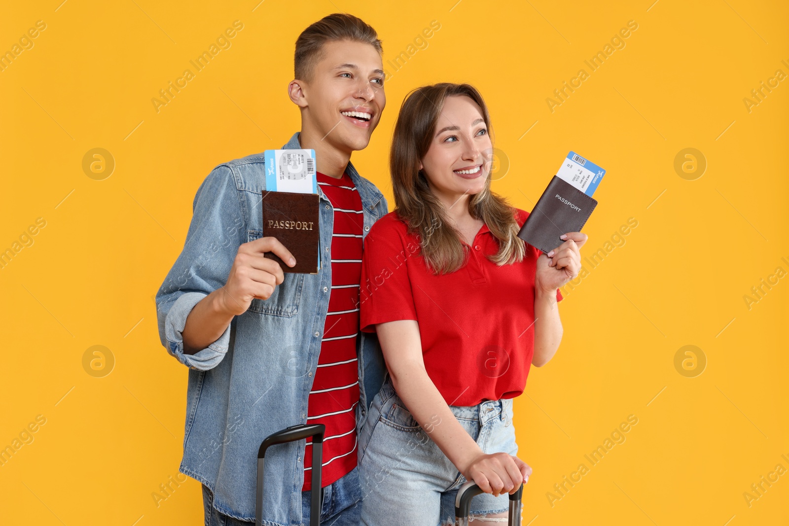 Photo of Happy travellers with passports and tickets on yellow background