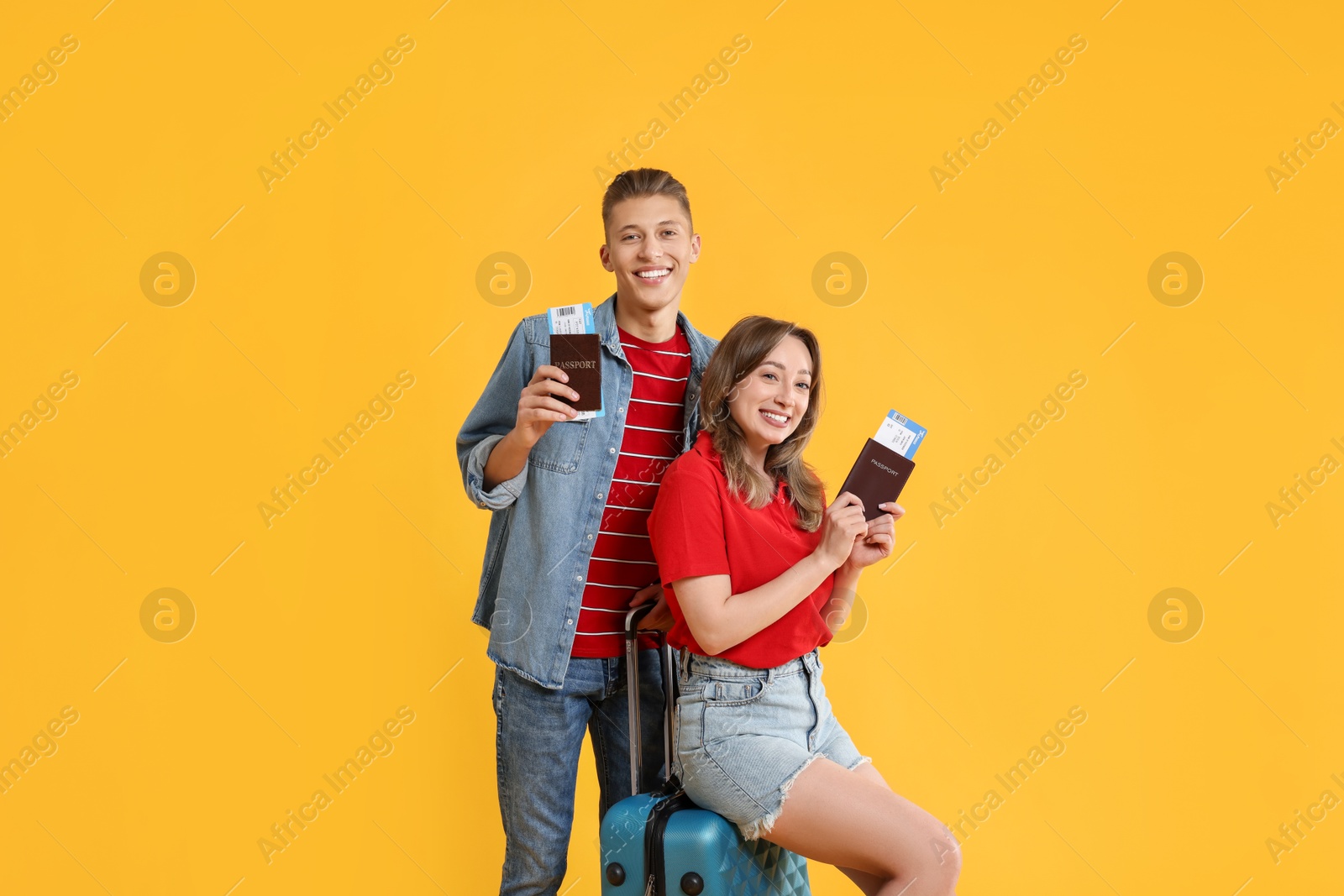 Photo of Happy travellers with suitcase, passports and tickets on yellow background