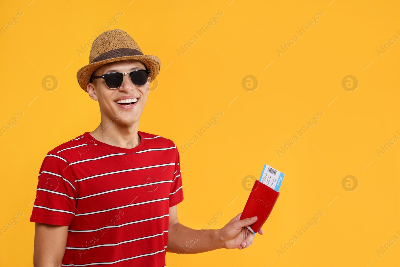 Photo of Happy traveller in sunglasses with passport and ticket on yellow background, space for text