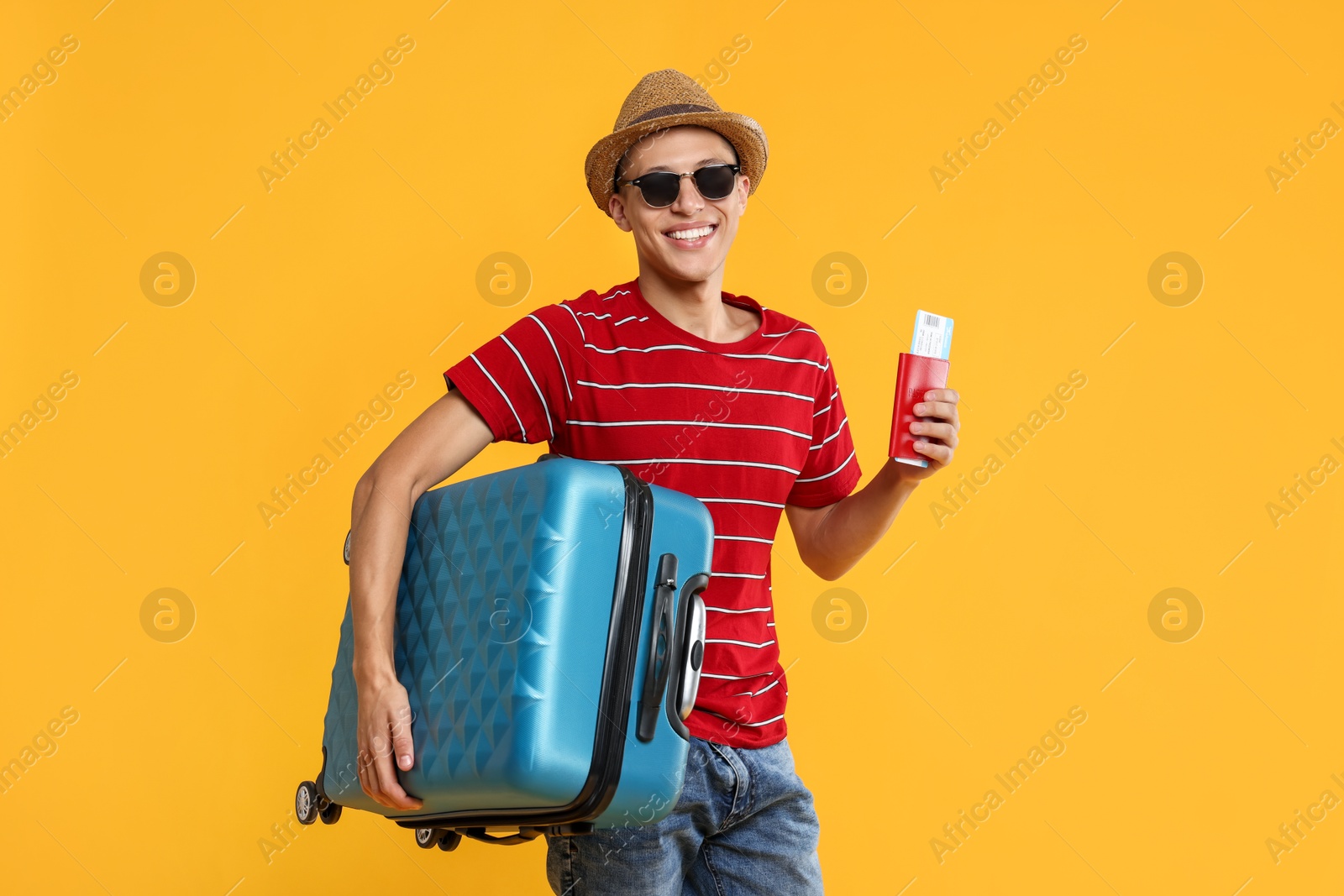 Photo of Happy traveller with suitcase, passport and ticket on yellow background