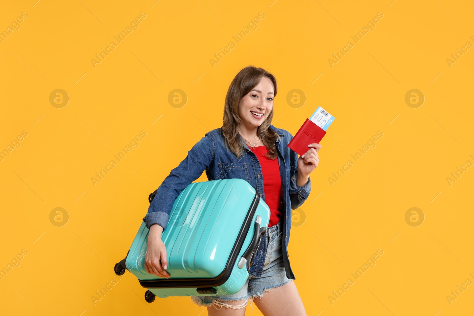 Photo of Happy traveller with suitcase, passport and ticket on yellow background