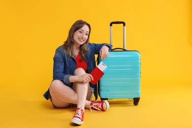 Photo of Happy traveller with suitcase, passport and ticket on yellow background