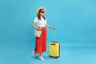 Photo of Happy traveller in sunglasses with suitcase on light blue background