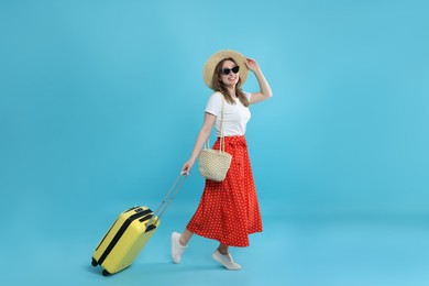 Happy traveller in sunglasses with suitcase on light blue background