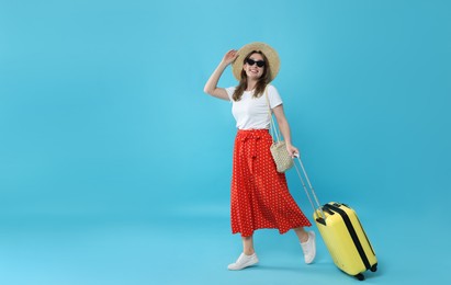 Photo of Happy traveller in sunglasses with suitcase on light blue background