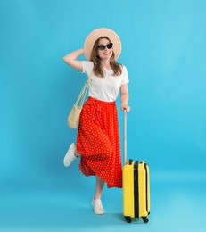 Happy traveller in sunglasses with suitcase on light blue background