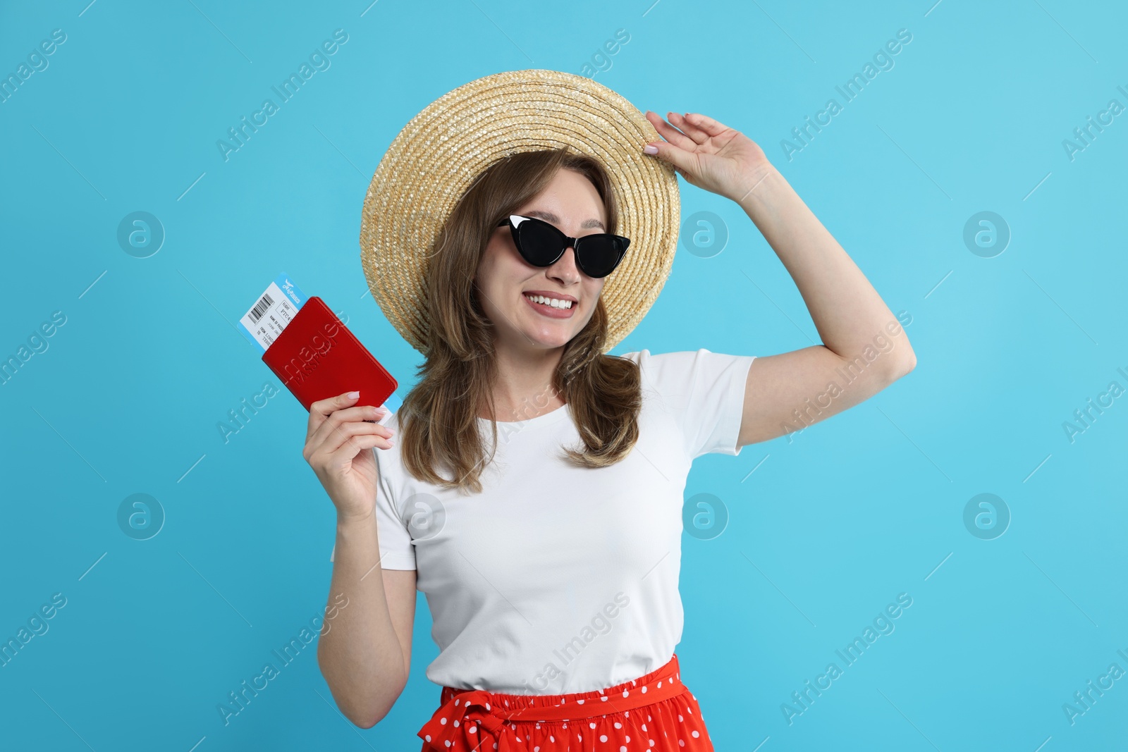 Photo of Happy traveller in sunglasses with passport and ticket on light blue background