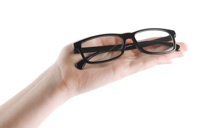 Photo of Woman holding glasses with black plastic frame on white background, closeup