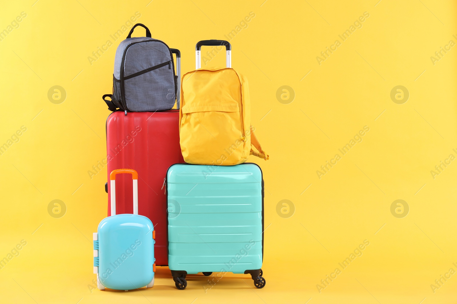 Photo of Travel abroad. Packed suitcases and backpacks on yellow background