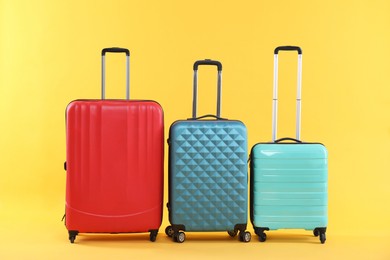 Different packed suitcases on yellow background. Travel luggage