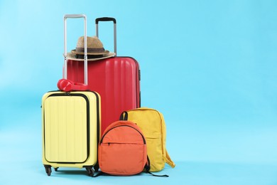 Photo of Travel abroad. Packed suitcases, backpacks, headphones and hats on light blue background. Space for text