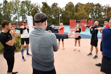 Photo of Group of people exercising and stretching outdoors