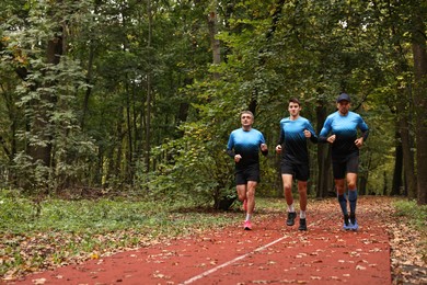 Photo of Group of athletic people running in park. Space for text